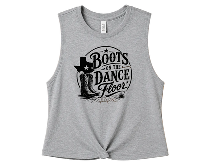 A heather gray sleeveless crop top with a black graphic print reading 'Boots on the Dance Floor' with cowboy boots and a hat, displayed flat against a solid peach background.
