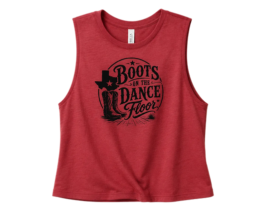 A sleeveless heather red crop top featuring a black graphic print on the front that reads 'Boots on the Dance Floor' with a cowboy boot and Texas-shaped star design, displayed flat against a light beige background.
